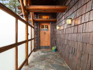 Experience rustic charm with this inviting entryway, featuring a beautiful wooden door with a classic knocker and a frosted glass window.