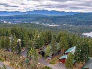 Nestled amidst a lush pine forest, this stunning property offers breathtaking panoramic views of distant mountains and a serene lake.
