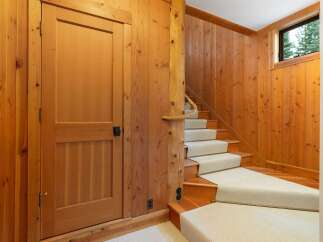 Step into a warm and inviting atmosphere with this stunning wooden staircase, featuring a plush carpet runner for comfort and style.