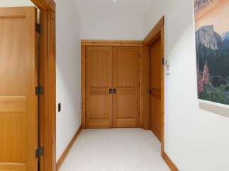 Step into this inviting hallway featuring warm wooden doors and trim, complemented by plush carpeting for a cozy ambiance.