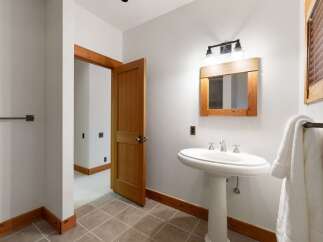 This charming bathroom features a pedestal sink with elegant chrome fixtures, complemented by a rustic wooden-framed mirror.