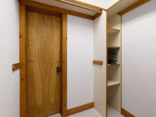 Discover ample storage solutions in this charming space, featuring a beautiful wooden door and built-in shelving.