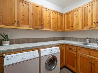 This laundry room features ample storage with beautiful natural wood cabinetry, both above and below the countertops.