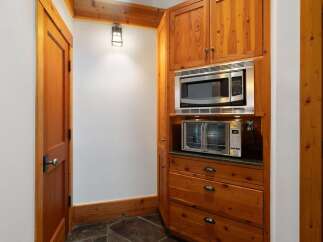 This charming kitchen nook features warm, natural wood cabinetry and a built-in microwave and toaster oven, perfect for a cozy culinary space.