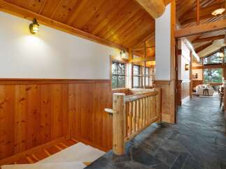 Experience rustic charm in this mountain home featuring a stunning wood-paneled interior and a grand vaulted ceiling with exposed beams.