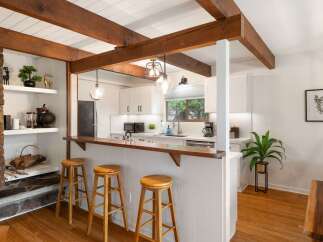 Experience rustic charm in this inviting kitchen featuring exposed wooden beams and a cozy stone fireplace.