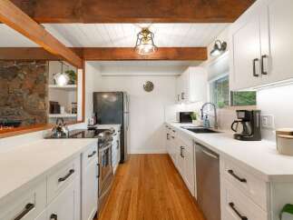 This charming kitchen features a rustic stone fireplace and exposed wooden beams, creating a warm and inviting atmosphere.