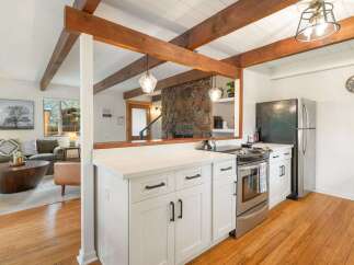 Experience rustic charm in this inviting kitchen featuring white shaker cabinets and a sleek stainless steel range.