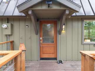 Step into this charming home through a beautiful wooden door, perfectly complemented by the rustic wooden deck and railings.