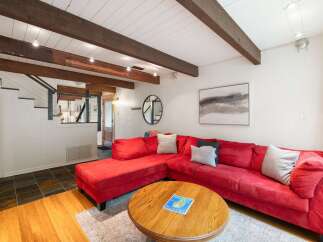 Experience cozy living in this charming living room featuring a vibrant red sectional sofa and a rustic wooden coffee table.