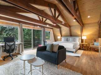 Experience rustic charm and modern comfort in this stunning bedroom featuring exposed wooden beams and a vaulted ceiling.