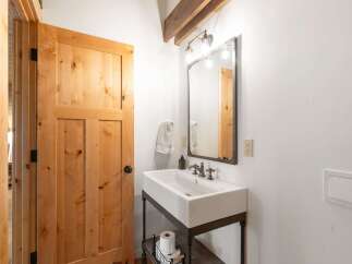 This charming bathroom features a rustic wooden door and a modern vessel sink with vintage-style fixtures.