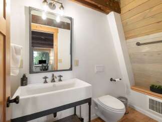 This rustic bathroom features a charming farmhouse sink with industrial-style metal accents and a large, framed mirror.