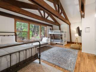 Experience rustic charm in this spacious bedroom featuring a cozy metal-frame bed and a convenient bunk bed setup, perfect for families or groups.