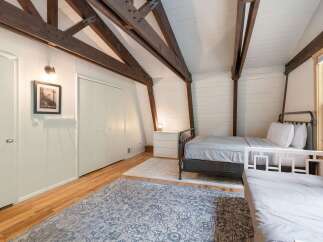 This charming bedroom features a rustic aesthetic with exposed wooden beams and white shiplap walls.