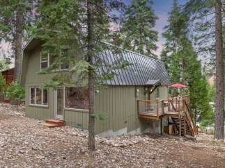 Nestled amongst tall pine trees, this charming home offers a serene mountain retreat.