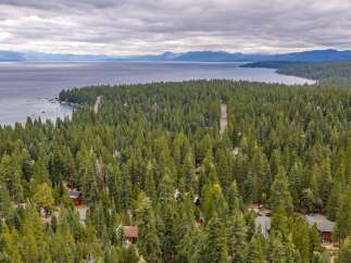 Nestled amidst a dense forest, this property offers a serene escape with stunning views of a vast lake and distant mountains.