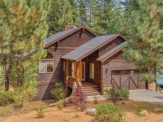 Nestled amidst tall pine trees, this charming wooden home offers a rustic retreat with its natural wood siding and shingle roof.