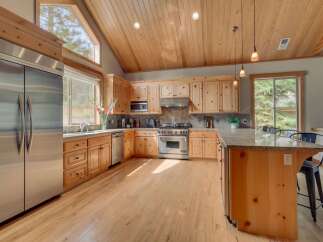 Experience rustic charm in this spacious kitchen featuring warm, knotty pine cabinetry and vaulted wood-paneled ceilings.