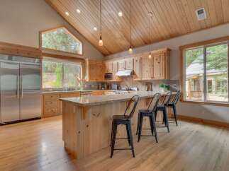Experience rustic charm in this spacious kitchen featuring light wood cabinetry and a large granite-topped island perfect for casual dining.