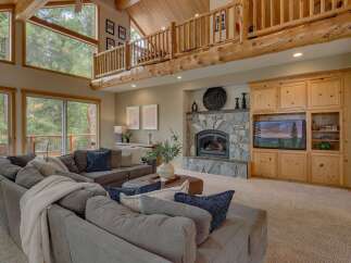 Experience rustic charm and modern comfort in this stunning living room, featuring a grand stone fireplace and a beautiful wooden entertainment center.