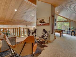 Experience rustic charm in this loft game room, featuring a pool table and comfortable seating areas.