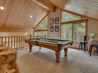 Enjoy endless entertainment in this rustic game room, featuring a classic pool table perfect for friendly competitions.