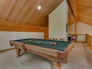 Enjoy endless entertainment in this game room featuring a classic pool table and a cozy seating area.