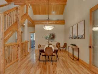 Experience rustic charm in this spacious dining area featuring a beautiful log staircase and exposed wooden beams.