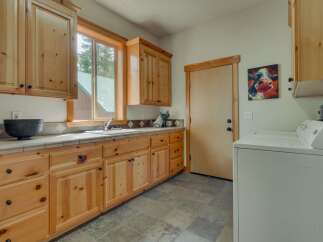 This laundry room features beautiful natural wood cabinetry and countertops, offering ample storage and a warm, inviting aesthetic.