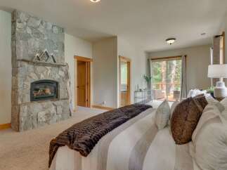 Experience ultimate comfort in this luxurious master bedroom, featuring a stunning stone fireplace perfect for cozy evenings.