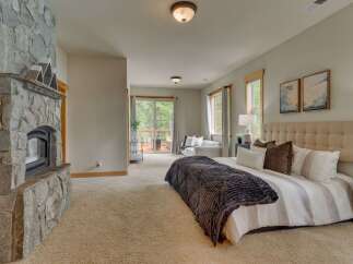 Experience ultimate comfort in this luxurious master suite, featuring a stunning stone fireplace and a private balcony with scenic forest views.