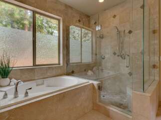 Indulge in relaxation in this luxurious bathroom featuring a spacious soaking tub and a separate glass-enclosed shower.