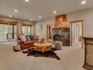 Cozy up by the stunning stone fireplace with a unique copper hood in this inviting living room.