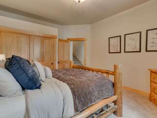 Experience rustic charm in this cozy bedroom, featuring a sturdy log bed and warm wooden doors.