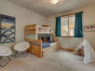 This charming children's bedroom features a sturdy wooden bunk bed with a pull-out trundle, perfect for sleepovers.