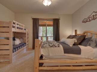 This charming bedroom features a cozy bunk bed perfect for families and a comfortable queen-size bed adorned with plush pillows and a luxurious throw.