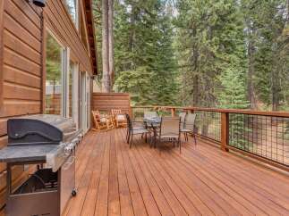 Enjoy outdoor living on this spacious wooden deck, perfect for entertaining or relaxing amidst the serene forest.