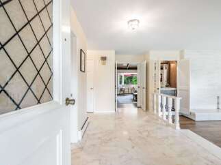Step into this inviting entryway featuring elegant marble flooring and a decorative glass door.