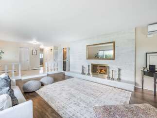 Experience cozy evenings by the fireplace in this inviting living room, featuring a striking white brick accent wall and a large decorative mirror.