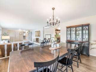 This spacious dining room features a large wooden table with black chairs, perfect for family gatherings.
