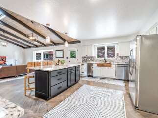 Experience modern living in this stunning kitchen featuring a large island with granite countertops and dark cabinetry.