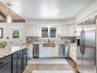This stunning kitchen boasts a large island with dark cabinetry and a granite countertop, perfect for meal prep and entertaining.