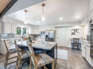 Experience modern living in this stunning kitchen featuring a large granite island with bar seating, perfect for casual dining and entertaining.