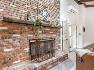 Cozy up by the rustic brick fireplace, featuring a charming wooden mantel adorned with decorative accents and a unique starburst wall art.
