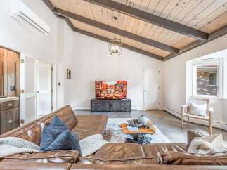 Experience modern living in this stunning living room, featuring a vaulted wood-beamed ceiling and a sleek entertainment center.
