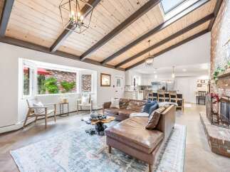 Experience modern living in this stunning open-concept home, featuring a vaulted wood-beamed ceiling with a skylight that floods the space with natural light.