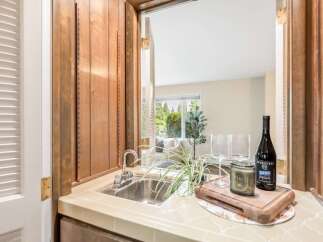 Discover this charming wet bar, perfect for entertaining, featuring a stainless steel sink and ample counter space.