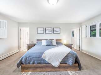 This spacious bedroom features a comfortable king-size bed with a quilted blue comforter and a decorative white throw.