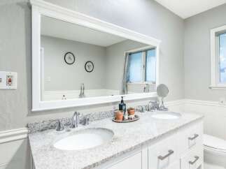 This modern bathroom features a spacious double vanity with a granite countertop and sleek chrome fixtures.
